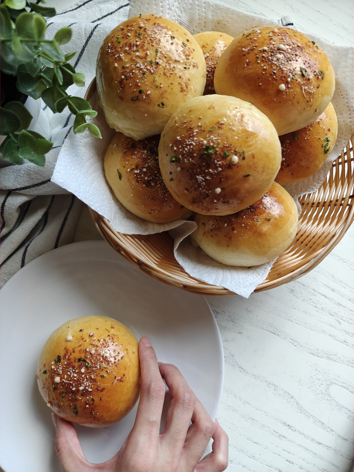 Golden herb-dusted bread rolls topped with truffle cheese in a wicker basket